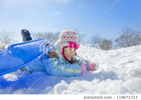 Girl sledding in a snowy park Girl sledding in a snowy park 119672153
