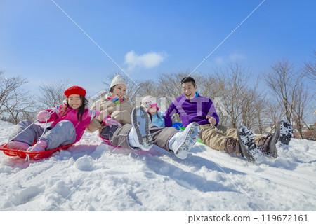 A family of four sledding in a snowy park A family of four sledding in a snowy park 119672161