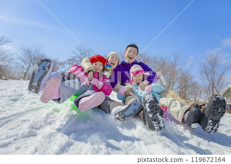 A family of four sledding in a snowy park 119672164