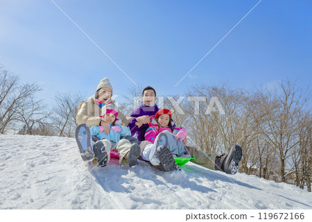 A family of four sledding in a snowy park A family of four sledding in a snowy park 119672166
