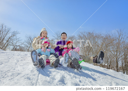 A family of four sledding in a snowy park A family of four sledding in a snowy park 119672167