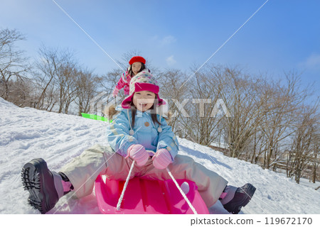 姊妹們在白雪皚皚的公園裡滑雪橇 119672170