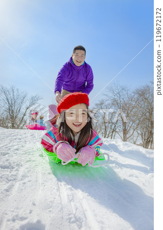 Parents and children sledding in a snowy park 119672172