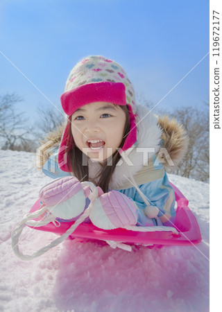 Girl sledding in a snowy park 119672177
