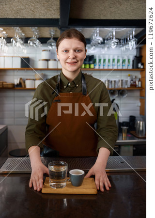 Glass of water and coffee cup on wooden tray in female barista hands Glass of water and coffee cup on wooden tray in female barista hands 119672624