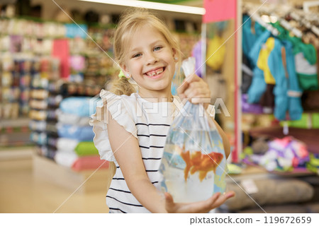 Portrait of cute smiling little girl holding packet with new fish pet 119672659