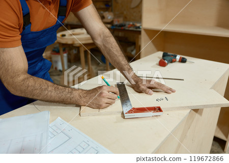 Handyman measuring with ruler during furniture production process at workshop 119672866