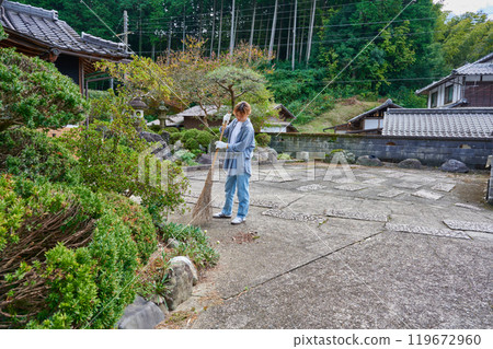 Woman sweeping the garden Countryside Old house Inn Life 119672960