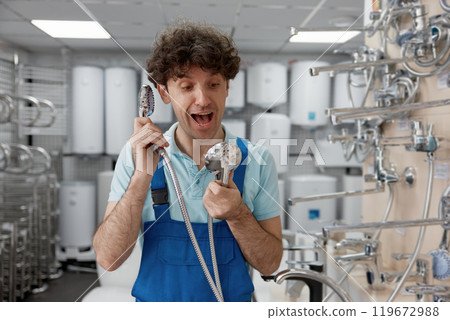 Plumber holding shower head like telephone while shopping at plumbing store 119672988