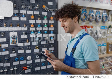 Salesman merchandising and checking plumbing hardware assortment on shop display 119673008