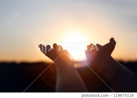 New Year's sunrise, brilliant light and rays of light shining through hands stretched out toward the rising sun, concept of hope and wishes for the future New Year's sunrise, brilliant light and rays of light shining through hands stretched out toward the rising sun, concept of hope and wishes for the future 119673116