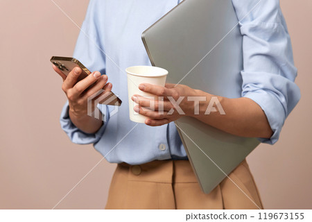 businesswoman working and holding smartphone, laptop and paper coffee cup 119673155