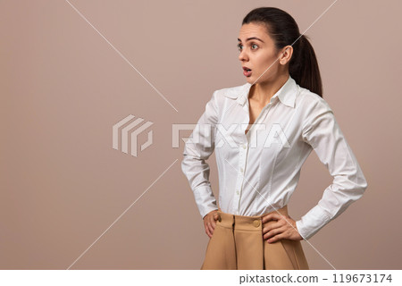 surprised Caucasian businesswoman lady in white shirt and beige pants looing at the side, copy space 119673174