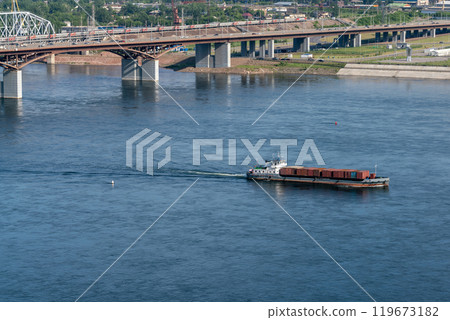 A cargo ship with containers sails under a bridge. River transport. 119673182