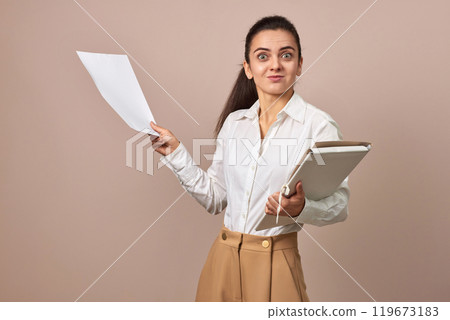 surprised businesswoman in white shirt holding folders with documents on beige background 119673183