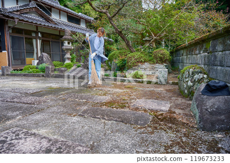 Woman sweeping the garden Countryside Old house Inn Life 119673233