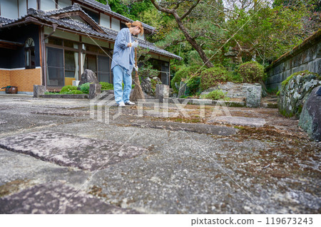 Woman sweeping the garden Countryside Old house Inn Life 119673243