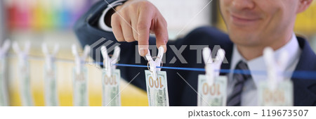 Smiling entrepreneur hangs dollar bills on clothesline 119673507