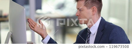 Disappointed employee looks at computer monitor at workplace 119673508