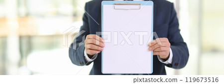 Office worker holds clipboard with blank paper in hallway 119673516