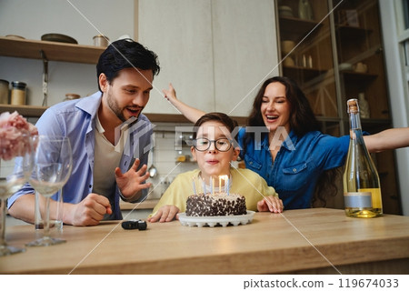 Celebrating a childs birthday with cake, candles, and joyful parents at home 119674033