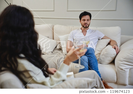 A couple enjoys a relaxed evening with cocktails in a cozy living room 119674123
