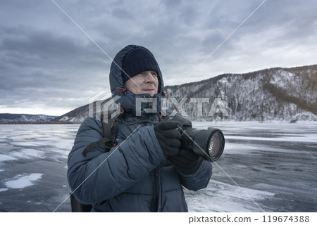 A winter photographer is taking pictures of a frozen landscape in the cold weather A winter photographer is taking pictures of a frozen landscape in the cold weather 119674388