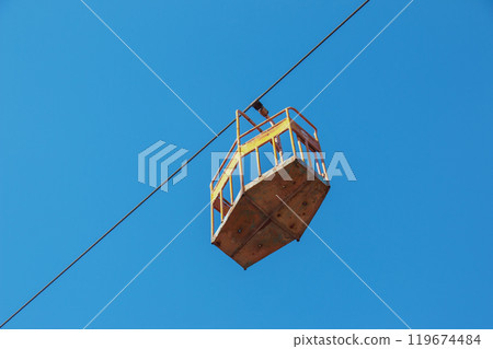 Old cable car in Dnepropetrovsk. Cable car cabins against the background of the blue sky and the urban landscape. 119674484
