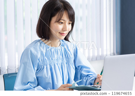 Woman taking notes while using a PC 06 119674655