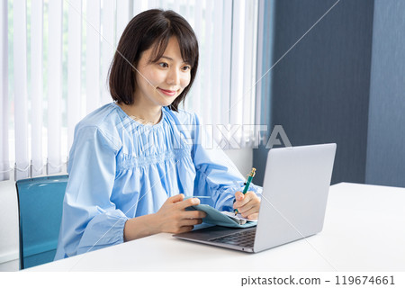 Woman taking notes while operating a PC 11 119674661