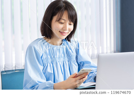 開啟電腦並操作智慧型手機的女性 01 119674670
