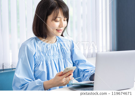 Woman opening a PC and using a smartphone 02 119674671
