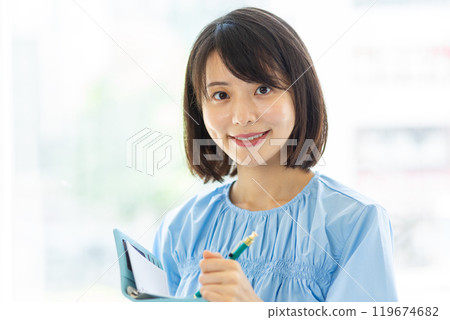 Smiling woman taking notes in her notebook 01 119674682
