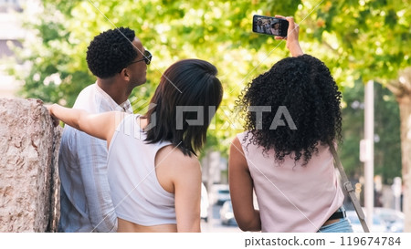 Diverse friends taking selfie via smartphone in city 119674784