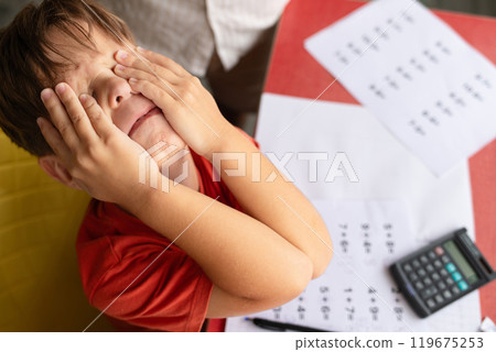 A child with dyscalculia and dyslexia is on the verge of tears while trying to complete his math homework. 119675253