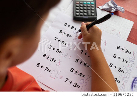 Over the shoulder view of a child who has dyslexia and dyscalculia doing math homework. 119675255