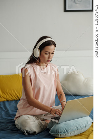 Listening to Music and Working on Laptop in Bed 119675415