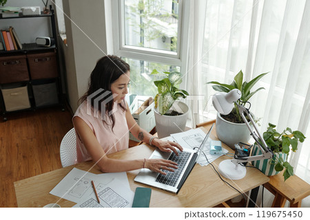 Asian Woman Working at Home Office Desk Near Window Asian Woman Working at Home Office Desk Near Window 119675450