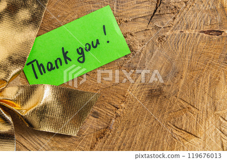 A word of thanks to a small green leaf on a piece of wood next to the bow 119676013