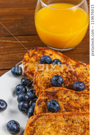 French toast on a white plate with blueberries and orange juice for breakfast 119676015