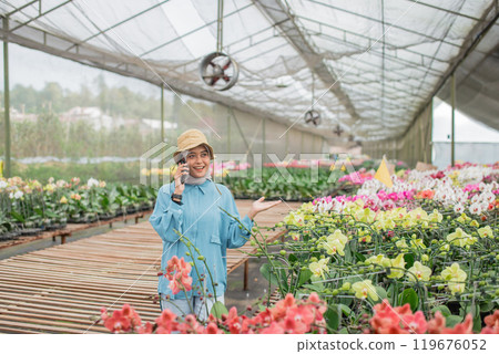 A happy gardener in a colorful greenhouse filled with beautiful orchids 119676052