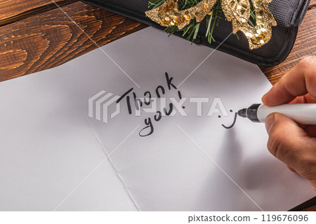 A person draws a smiley face on a piece of paper for the words of thanks 119676096