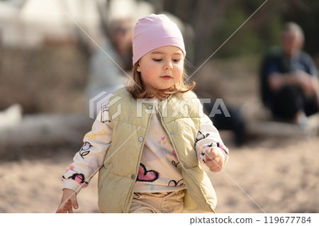 A charming and playful child enjoys delightful moments spent outdoors, dressed in a cozy and cute outfit 119677784
