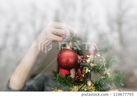 Person through a window hanging Xmas decorations 119677795