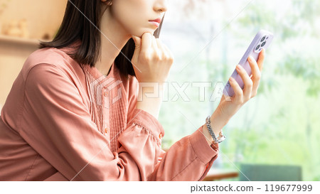 A young woman/businesswoman thinking while looking at her smartphone 119677999