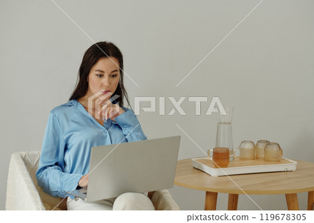Woman Wearing Blue Shirt Working on Laptop 119678305