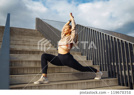 Fitness woman in fashionable sportswear is doing sports outdoors. The concept of active lifestyle. 119678358