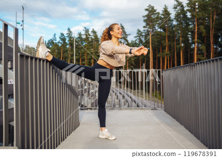Fitness woman in fashionable sportswear is doing sports outdoors. The concept of active lifestyle. 119678391