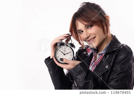 A Young Woman is Holding an Alarm Clock While Dressed in a Trendy and Stylish Outfit A Young Woman is Holding an Alarm Clock While Dressed in a Trendy and Stylish Outfit 119678401