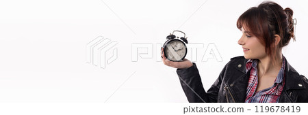 A Young Woman Enthusiastically Holding an Alarm Clock While Dressed in a Trendy Outfit A Young Woman Enthusiastically Holding an Alarm Clock While Dressed in a Trendy Outfit 119678419